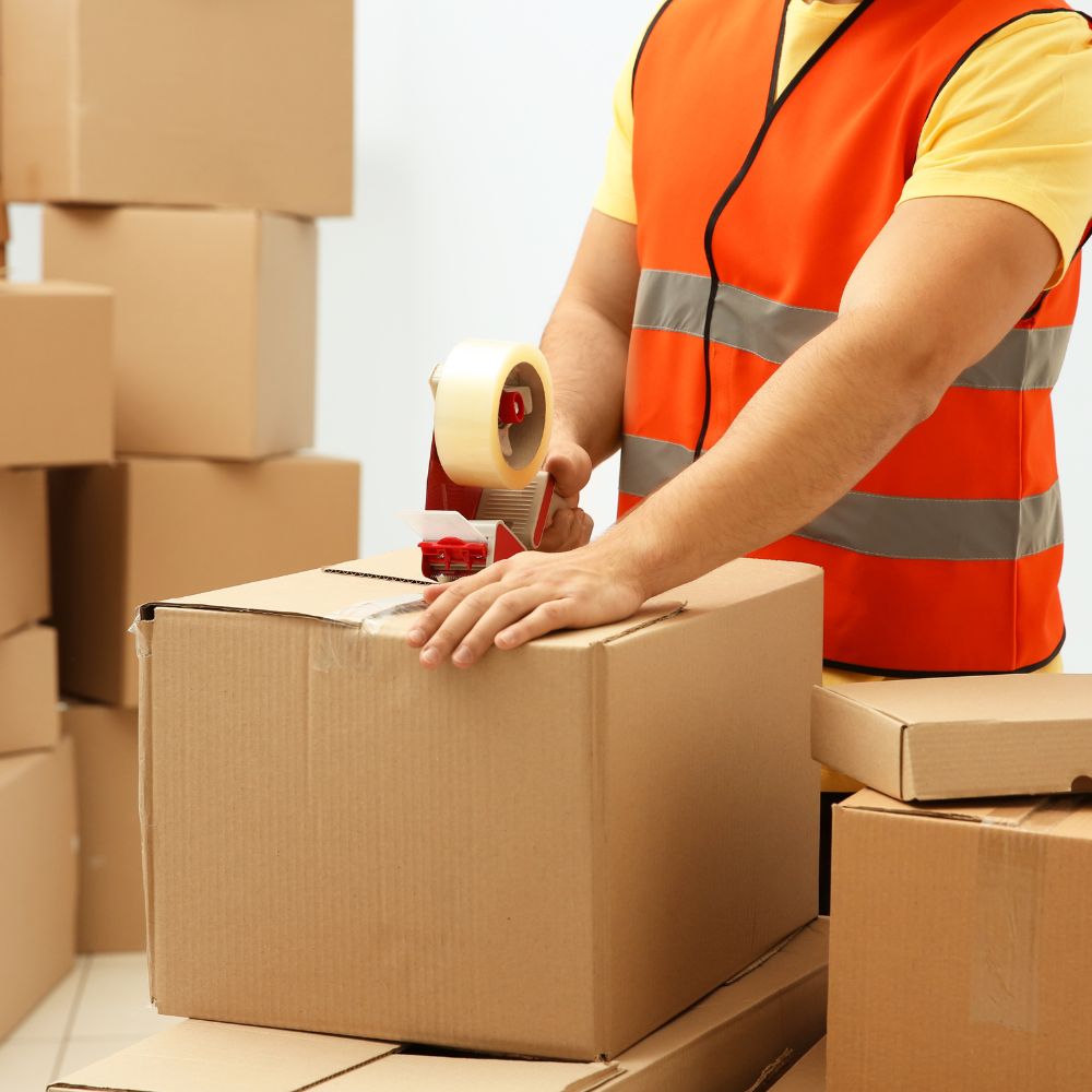 Image of polypropylene tape being applied to a corrugated shipping box in a warehouse.